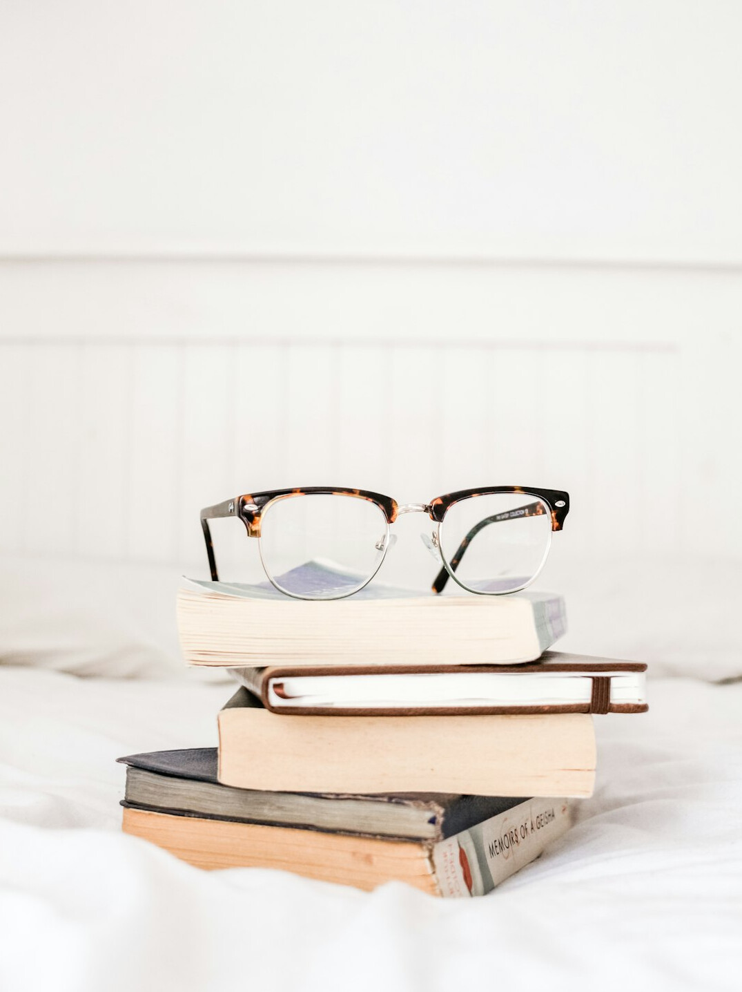 Stack of old mystery novels with reading glasses and coffee cup on wooden table